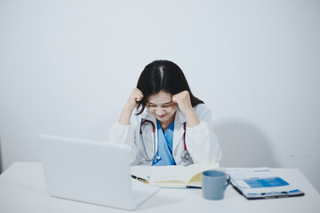 Middle aged female doctor working on laptop in doctor's room