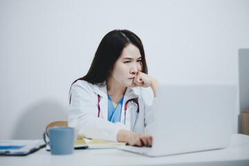 Middle aged female doctor working on laptop in doctor's room