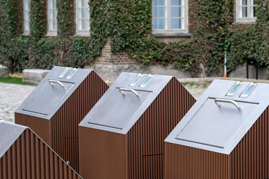 Urban exterior perspective featuring a public waste container positioned near local architecture, combining practical design with sustainable ecofriendly cues