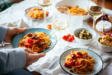Friends having a pasta dinner with wine at home.