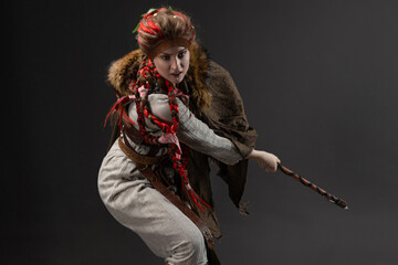 Fantasy Viking heroine holding Scandinavian axe in natural dress with fur cloak, axe blow