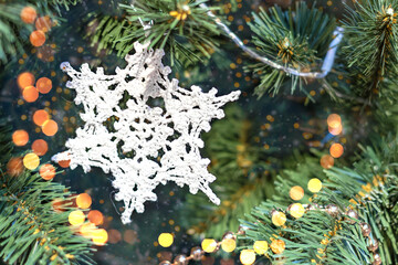 Handmade knitted snowflake decoration on Christmas tree. Copy space
