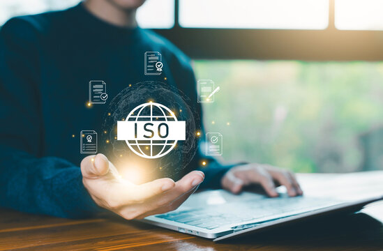 Businessman holding digital ISO icon with certification documents, symbolizing international standards, quality control assurance, compliance, regulation, auditing, and global business certification.