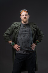 Bald man in dystopian raincoat with textured holes and goggles, charismatic cyberpunk.