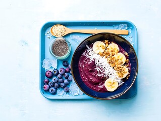 Healthy acai bowl with banana and blueberries on a blue tray