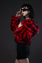 Young woman in bright red faux fur coat with short hair, bold kitsch look