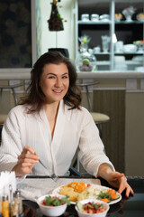 Breakfast at the hotel, a young brunette woman in a white terry dressing gown, eating in the hotel dining room, medical clinic or sanitorium