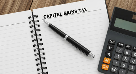 Capital gains tax business finance goals notebook page with pen and calculator planning financial strategy and accounting note taking in office setting