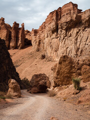 Dramatic red rock canyon in Kazakhstan mountains, nature-carved curves under vast sky.