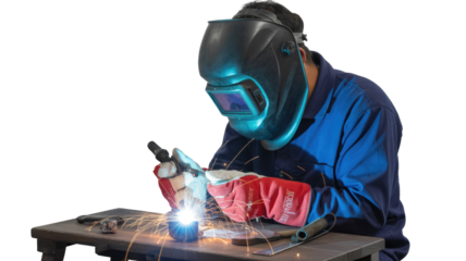 A skilled welder in blue coveralls and safety gear performs metalwork, creating bright sparks with a welding torch on a work table. background removed
