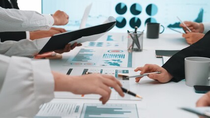 A diverse group of business professionals engages in a collaborative effort to analyze financial data, create charts, and discuss strategies in a modern office environment. SACTR - Powered by Adobe