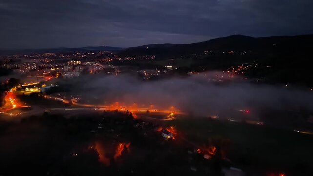 misty town with glowing roads, predawn mist envelops illuminated highways and distant mountains