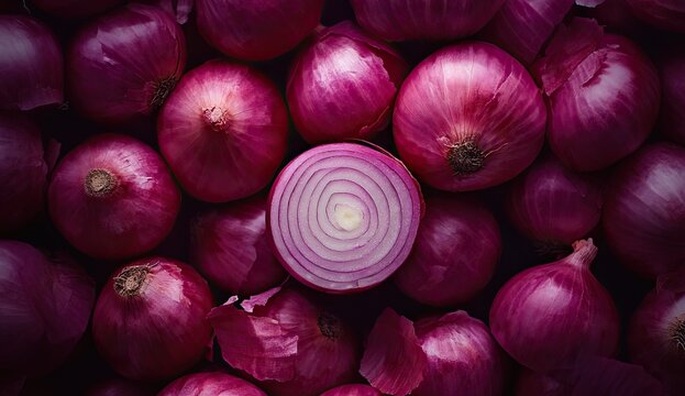 A pile of whole red onions with one sliced open, revealing layered purple rings, on a dark background