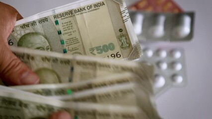 Hands Counting ₹500 Indian Cash with Medications on Table – Retirement & Healthcare Budget - Powered by Adobe