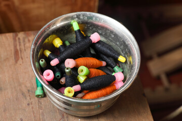 Bunch of yarn bobbins (also called pirns or spools) kept in a steel bowl.