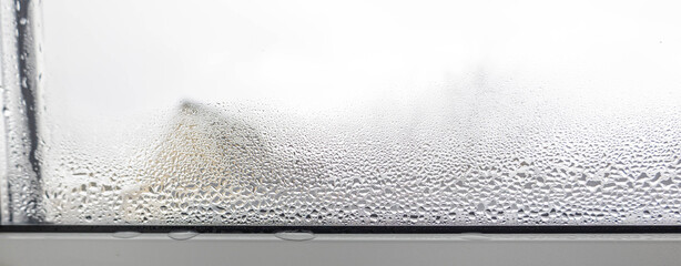 Close-up of heavy condensation and water drops on a foggy plastic windowpane in cold weather