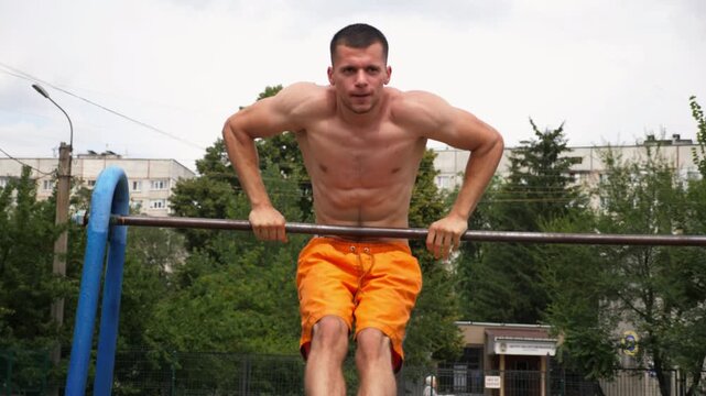 Sportsman performing dynamic workout routine on parallel bars, showcasing strength and determination in outdoor training environment, capturing the essence of athletic progression and physical fitness