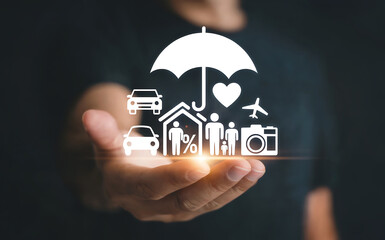 A persons hand holding a collection of white icons representing various types of insurance, including a house, car, family, heart, and airplane, under an umbrella