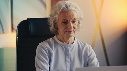 Elegant senior female financial analyst opening laptop and working in office - Powered by Adobe