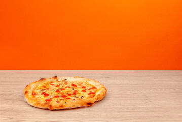 Pizza with tomato sauce, cheese, and mushrooms served on light wooden table with vivid orange background, perfect for food ads and menus