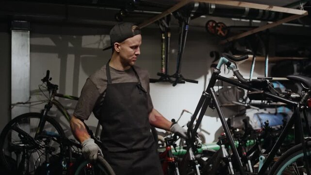 Young Caucasian man working in bicycle repair workshop, fixing wheel and attaching it to fork
