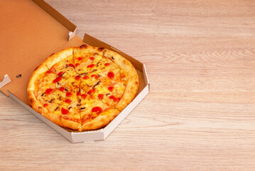 Pizza with melted cheese and tomato sauce in open cardboard box on wooden surface, perfect for takeaway or delivery service advertising
