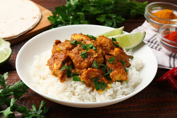 Chicken tikka masala with rice served on wooden table, closeup
