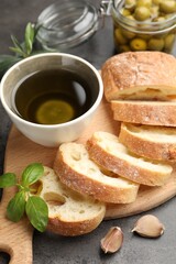 Slices of ciabatta, spices and olives on grey table, closeup