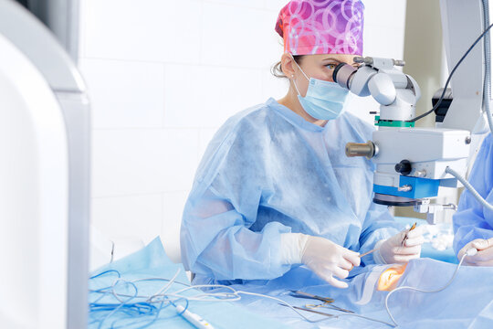 Ophthalmic surgeon performing blepharoplasty under microscope in a sterile operating room