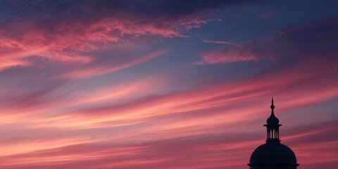 Dramatic sunset sky over the city with vibrant pink and purple clouds and silhouette of a building dome