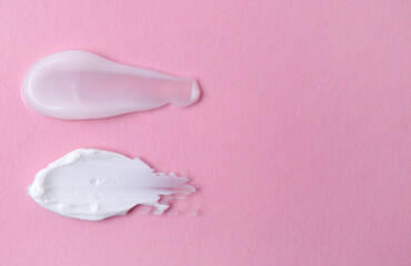 Samples of moisturizing creams on pink background, top view. Space for text