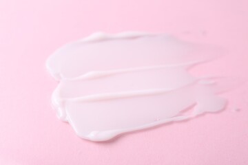Sample of moisturizing cream on pink background, closeup