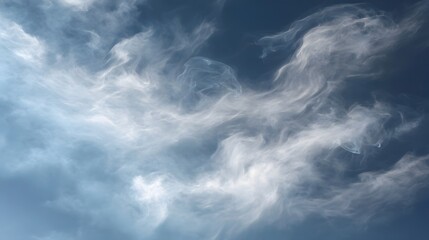 Obraz premium Wispy white clouds drift and swirl across a clear blue sky creating an ethereal and serene atmospheric pattern