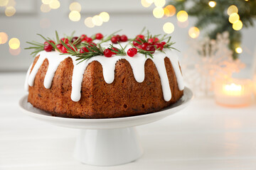 Tasty Christmas cake with icing, cranberries and rosemary on white wooden table, closeup