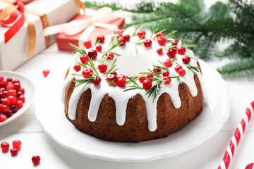 Tasty Christmas cake with icing, cranberries and rosemary on white wooden table, closeup
