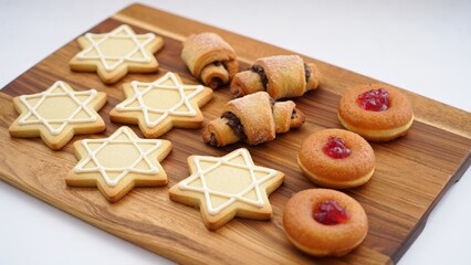 Assorted Hanukkah sweets – traditional sufganiyot and decorated cookies on festive serving boards. AI generated.