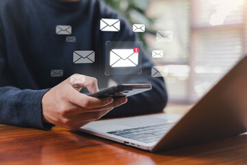 Person checking email notifications on a smartphone beside a laptop, illustrating mobile communication, digital messaging, online workflow, and modern productivity in a connected work environment.