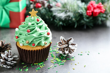 Christmas tree shaped cupcake and festive decor on grey table, closeup. Space for text