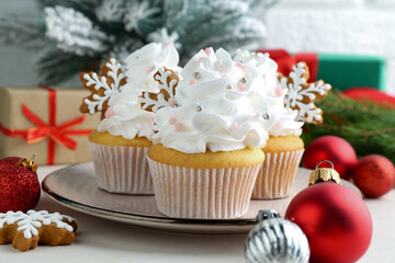 Tasty cupcakes with Christmas decor and gingerbread cookies on white table, closeup