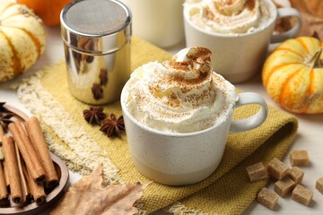 Tasty pumpkin latte with whipped cream, spices and fresh vegetables on white table, closeup