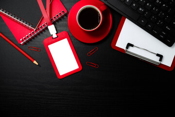 Red plastic badge with stationery and coffee on black wooden texture background. Template designed for employees of company