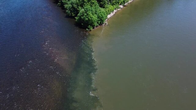 View from above. The confluence of two rivers with clean and dirty water. River pollution. Gold mining. An environmental disaster.