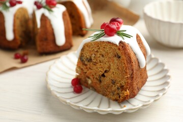 Slice of tasty Christmas cake with cranberries served on light wooden table, closeup