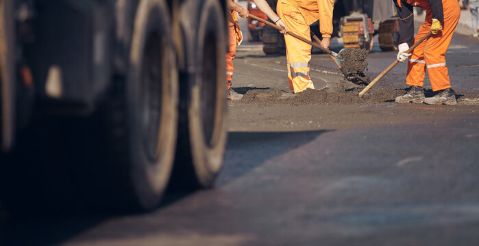 Construction worker working on a new asphalt layer on a public street.