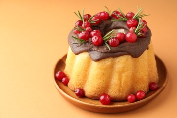 Tasty Christmas cake with cranberries on pale orange background, closeup. Space for text