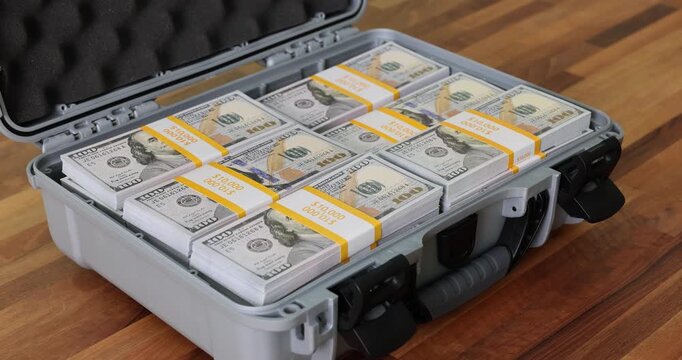 Neatly stacked bundles of dollar bills put into large briefcase. Suitcase holds cash securely symbolizing financial success. Frame interruption