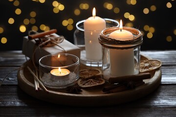 Christmas lanterns, matches and spices on wooden table against dark background with blurred lights, closeup. Bokeh effect