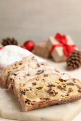 Cut traditional Stollen cake and Christmas decor on white table, closeup