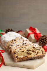 Cut traditional Stollen cake and Christmas decor on white table, closeup
