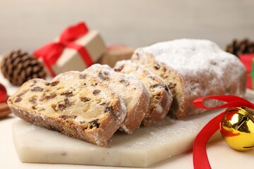 Cut traditional Stollen cake and Christmas decor on white table, closeup